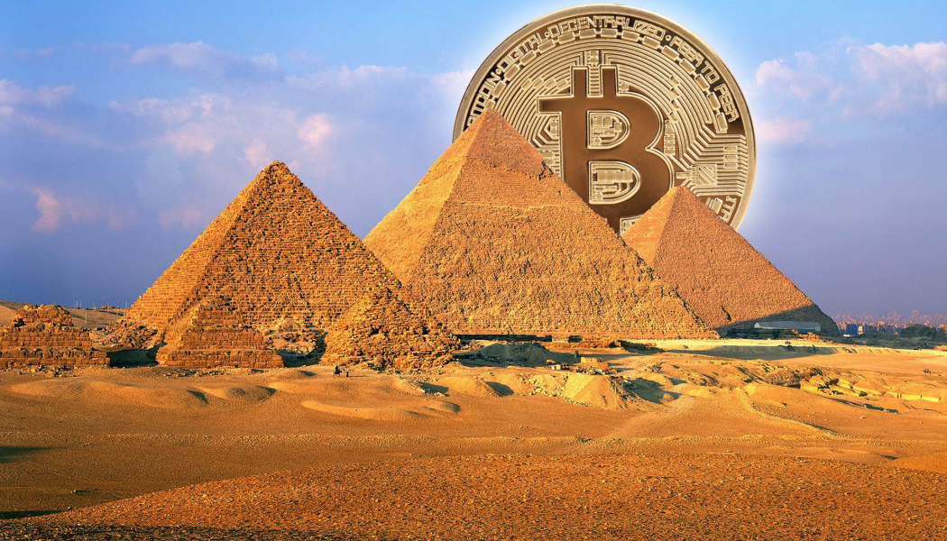 Bitcoin logo rising as sun over Pyramid's of Egypt